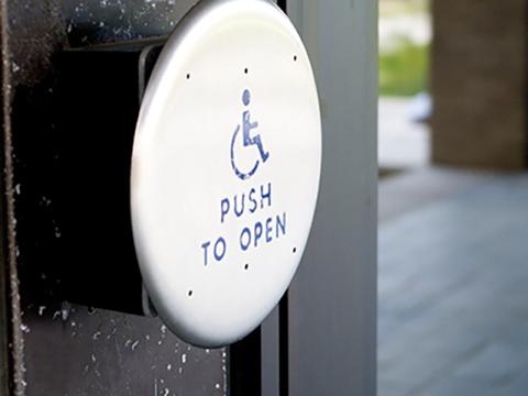 A close up of a hand press handicap assistant button to open the doors. 
